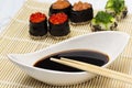 Chopsticks on a bowl with soy sauce. Sushi with caviar and seaweed on a bamboo sushi mat