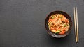 Chopsticks and bowl with wok noodles and vegetables on a black table background with a copy space Royalty Free Stock Photo