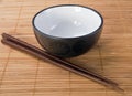 Chopsticks with ceramic bowl on bamboo mat