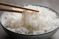 Chopsticks with cooked rice noodles over bowl on table, closeup Royalty Free Stock Photo