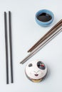 Chopsticks of different colors and materials, blue stone bowl with soy sauce and porcelain smiling anime cat on light blue Royalty Free Stock Photo