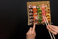 Chopsticks and fork in hand with sushi on black background Royalty Free Stock Photo