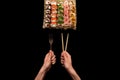 Chopsticks and fork in hand with sushi on black background Royalty Free Stock Photo