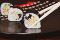 Chopsticks hold a sushi roll with salmon and fresh cucumber Royalty Free Stock Photo