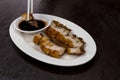 Chopsticks holding crispy roasted pork belly served with black s Royalty Free Stock Photo