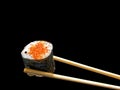 Chopsticks holding spicy salmon sushi wrap