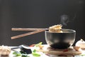 Chopsticks of instant noodles in cup with smoke rising and garlic on dark background, Sodium diet high risk kidney