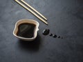 Chopsticks with leaking soy sauce on the black table. Puddle of soy sauce. Royalty Free Stock Photo