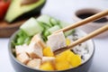 Chopsticks with meat over delicious poke bowl , closeup