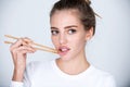 Chopsticks near sexy lips mouth. Pretty girl picking lips with chopsticks. Sexy mouth for sushi advertising. Concept of Royalty Free Stock Photo