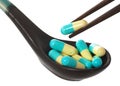 Chopsticks pick capsule from spoon Royalty Free Stock Photo