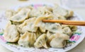 Chopsticks Pick Up Boiled Chinese Dumplings from a Plate.