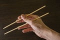 Chopsticks in the right hand on the background of wood Royalty Free Stock Photo