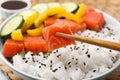 Chopsticks with salmon over delicious poke bowl , closeup
