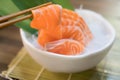 Chopsticks with Salmon sashimi with Salmon sashimi on ice in with bowl. japanese food in Asian restuarant Royalty Free Stock Photo