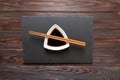 Chopsticks and soy sauce on black stone plate, wooden background Royalty Free Stock Photo