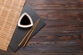 Chopsticks and soy sauce on black stone plate, wooden background with copy space Royalty Free Stock Photo