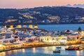 Chora port of Mykonos island with famous windmills, ships and yachts during colorful sunset. Aegean sea, Greece