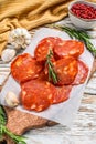 Chorizo sausage thin cut on a cutting board. Spanish salami with spices, paprika, pepper. Spicy food. White background Royalty Free Stock Photo