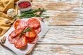 Chorizo sausage thin cut on a cutting board. Spanish salami with spices, paprika, pepper. Spicy food. White background. Top view. Royalty Free Stock Photo