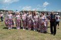 A chorus of elderly women in colorful dresses is sung next to a harmonist in a clearing at the Karatag music festival. Royalty Free Stock Photo