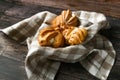 Choux cake on a wooden background. In a basket on a checkered towel. The apartment was lying. View from above. Chic with cottage