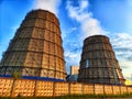 CHP cooling towers from which smoke is coming out against blue sky. A large pipe of a thermal power plant with smoke and Royalty Free Stock Photo