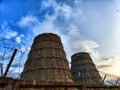 CHP cooling towers from which smoke is coming out against blue sky. A large pipe of a thermal power plant with smoke and Royalty Free Stock Photo