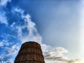 CHP cooling towers from which smoke is coming out against blue sky. A large pipe of a thermal power plant with smoke and Royalty Free Stock Photo