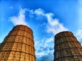 CHP cooling towers from which smoke is coming out against blue sky. A large pipe of a thermal power plant with smoke and Royalty Free Stock Photo