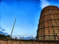 CHP cooling towers from which smoke is coming out against blue sky. A large pipe of a thermal power plant with smoke and Royalty Free Stock Photo