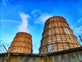 CHP cooling towers from which smoke is coming out against blue sky. A large pipe of a thermal power plant with smoke and Royalty Free Stock Photo