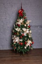 Chrismass tree with red bals and bow in fornt of bricks wall