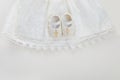 Christening background with baptism baby dress, shoes, and cross on pastel background