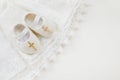 Christening background with baptism baby dress, shoes, and cross on pastel background