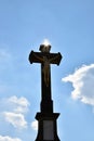 Christian Cross Against a Blue Sky. Stone christian cross on blue sky with clouds and sun rays Royalty Free Stock Photo