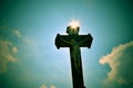 Christian Cross Against a Blue Sky. Stone christian cross on blue sky with clouds and sun rays Royalty Free Stock Photo