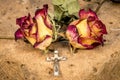 Christian cross on rosary and a dry yellow red roses lie on a sandstone Royalty Free Stock Photo