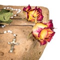 Christian cross on rosary and a dry yellow red roses lie on a sandstone Royalty Free Stock Photo