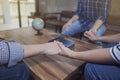 Christian friends holding hands together surrounded wooden table Royalty Free Stock Photo