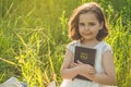 Christian girl holds bible in her hands. Reading the Holy Bible in a field during beautiful sunset. Concept for faith