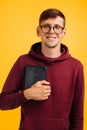 Christian man with glasses holds a Bible in his hands. Bible reading over isolated yellow background. Faith Royalty Free Stock Photo