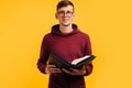 Christian man with glasses holds a Bible in his hands. Bible reading over isolated yellow background. Faith Royalty Free Stock Photo