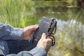 Christian man holding Holy Bible, religious cross and rosary beads by water and field background Royalty Free Stock Photo