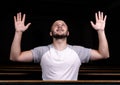 A Christian man in white shirt is sitting with his hands up and praying with humble heart in the church Royalty Free Stock Photo