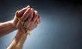 Christian praying with hands together with interlocked fingers and rosary