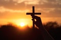 Christian religious concept. Silhouette Hand touching reaching for cross at sunset with glow and ray of the sun. Royalty Free Stock Photo