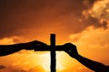 Christian religious concept. Silhouette Hands touching reaching for cross at sunset with glow and ray of the sun Royalty Free Stock Photo