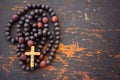 Christian rosary prayer with a cross on old black wooden background Royalty Free Stock Photo