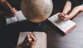 Christian small group praying together around a wooden table with bible page in homeroom. Christian group praying for globe and Royalty Free Stock Photo